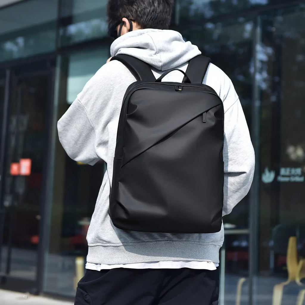 Men's large black waterproof PU backpack showing sewing thread detail and separate computer bag.