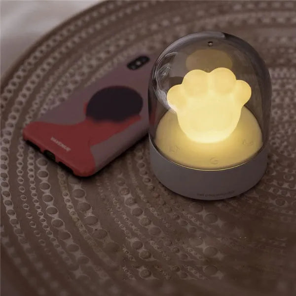 Grey cat paw shaped USB rechargeable night light with music box feature on wooden desk