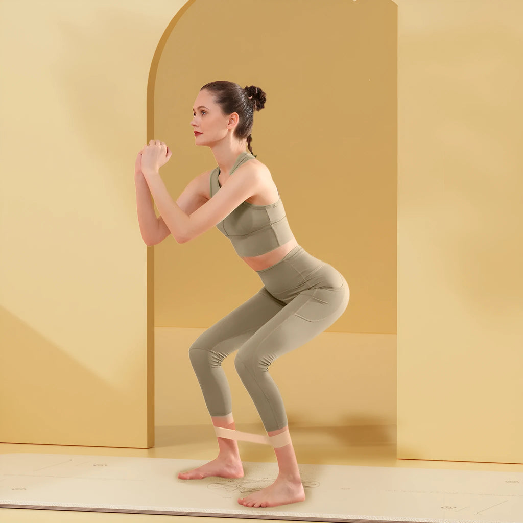Colour-coded elastic resistance band showing pink, orange, beige, and green options for fitness and yoga