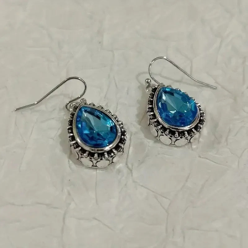 Retro style drop-shaped blue gem inlaid earrings in silver alloy, unisex jewellery on display