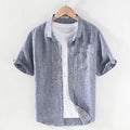 Men's short sleeve linen shirt with square collar in raw jute colour, laid flat.