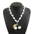 Gold-coloured women's necklace with a cherry fruit pendant on a pearl-style chain.