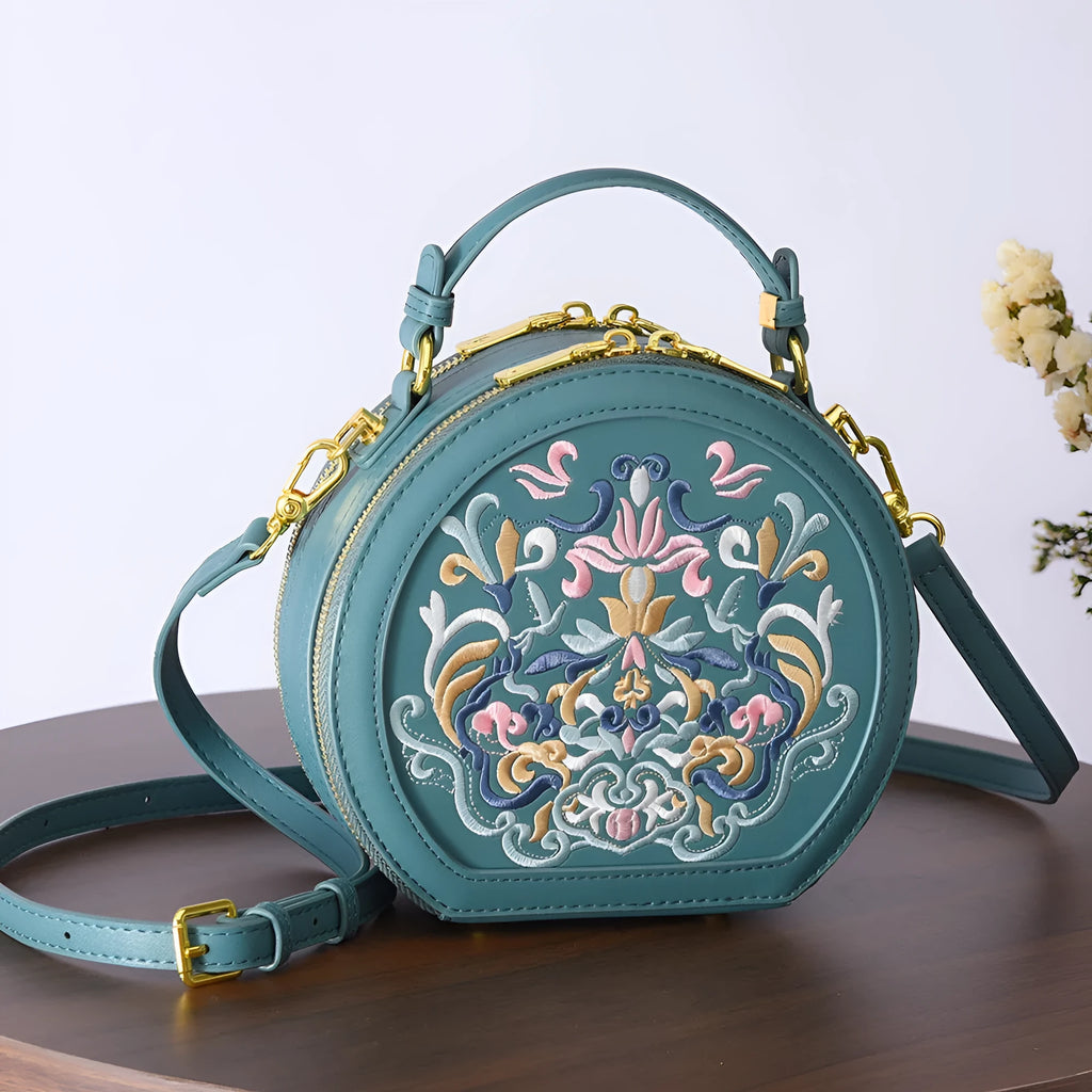 Small crossbody round bag in khaki with national-style embroidery and sewing line details, shown on a plain background