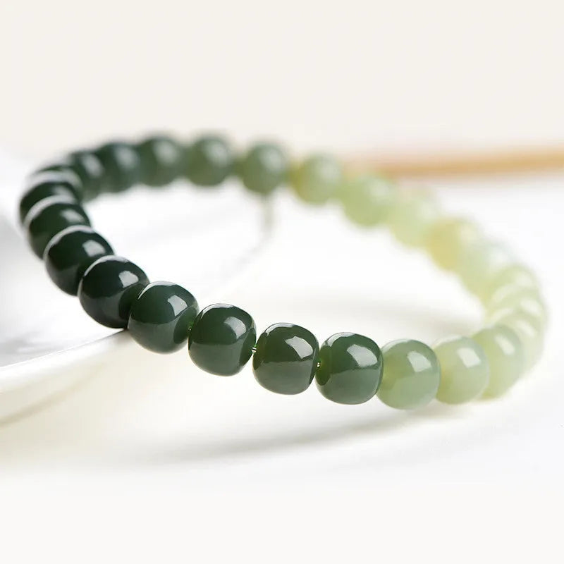 Natural Hetian jade bracelet with clear water gradient colour on wrist, showing polished beads.