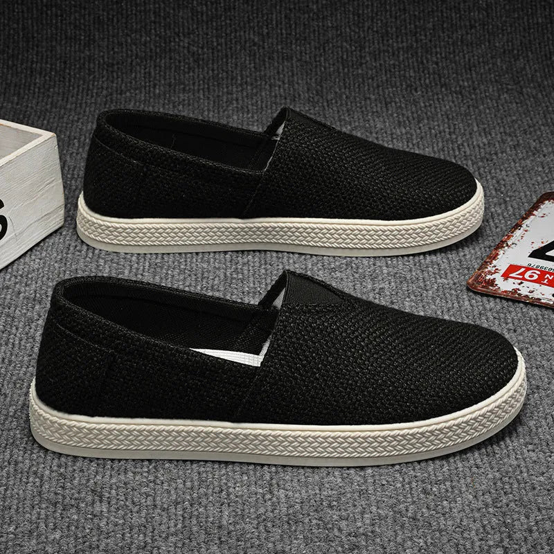 Men's beige linen canvas slip-on shoes with a round toe and shallow cut on a plain background.