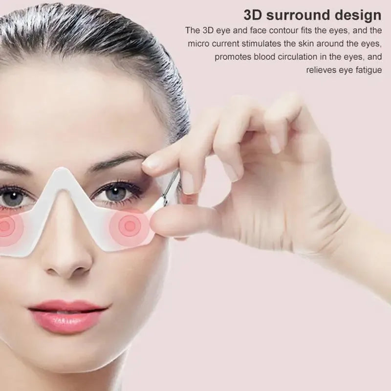 Pink and white micro-current eye massager with glasses-style frame on a grey background.
