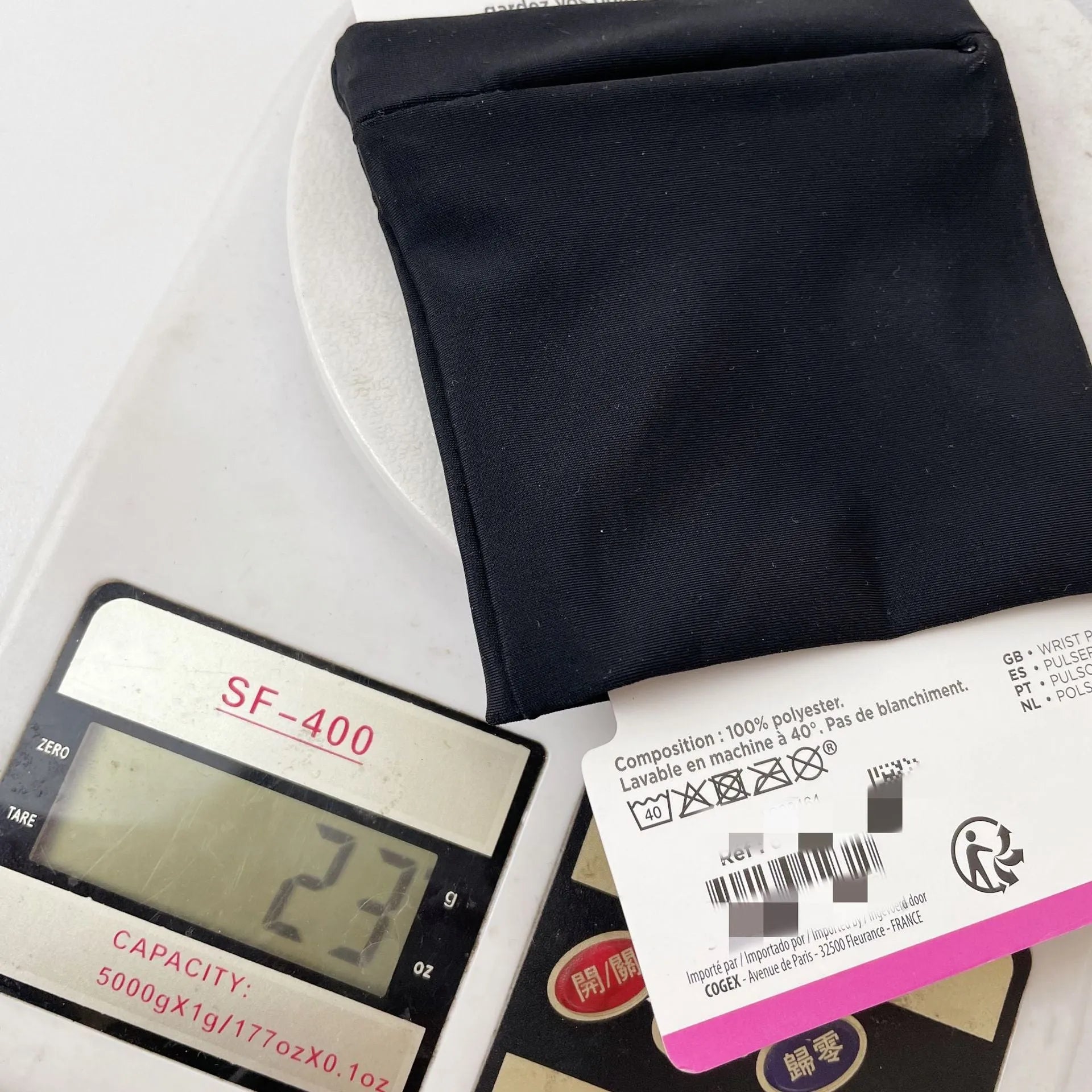 Compact 10 by 10.5 cm black armband sleeve for mobile phone, shown with packaging.