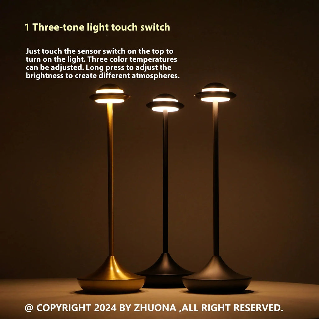 Metallic UFO-shaped rechargeable table lamp with touch controls in black finish on a wooden desk.