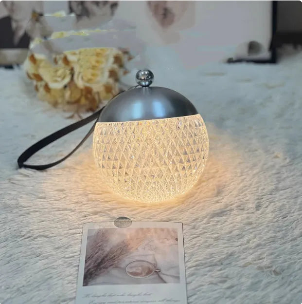 Small cylindrical portable night lamp with touch dimmer in chrome, gold, black, coppery brown, or white finish.