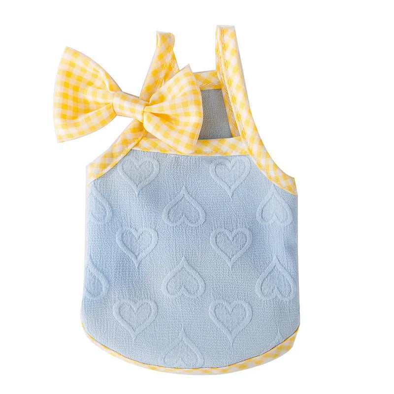 Small dog wearing a blue vest with a raised heart texture and bow suspenders on the front.