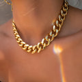 Gold coloured women's thick chain necklace on a white background.