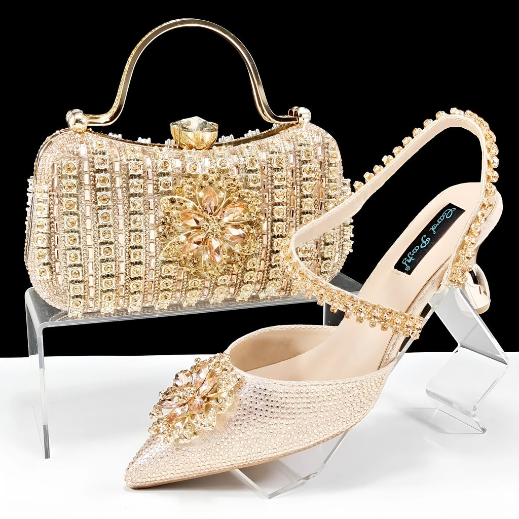 Women's black high heel and clutch bag set with rhinestone ankle chain and floral metal decoration.