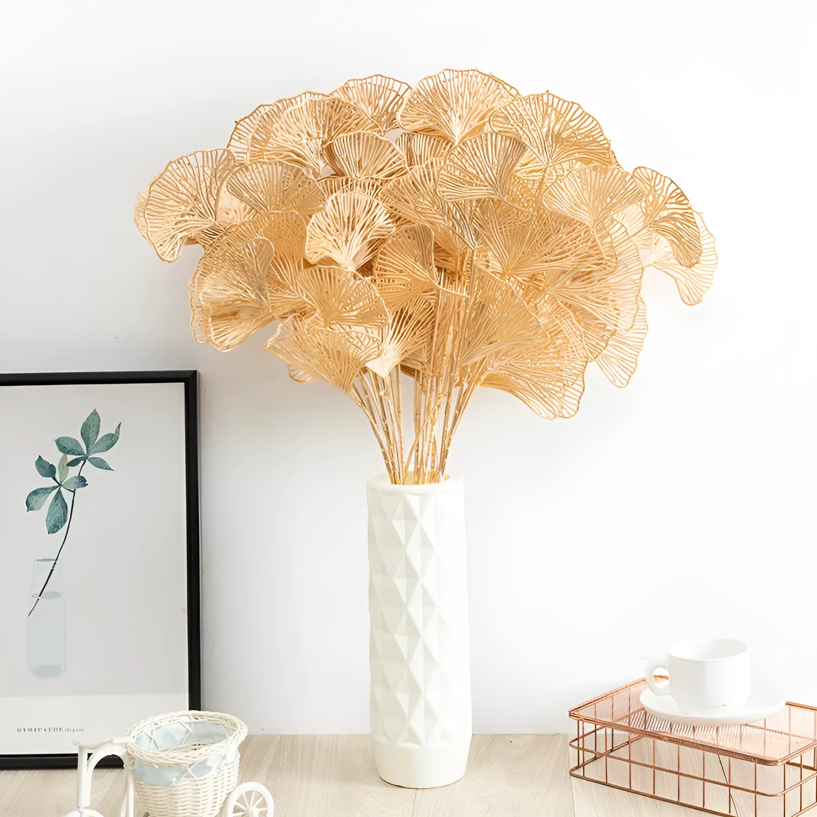 Gold plastic artificial flower arrangement featuring Persian eucalyptus and ginkgo leaves with single rose and peacock feathers