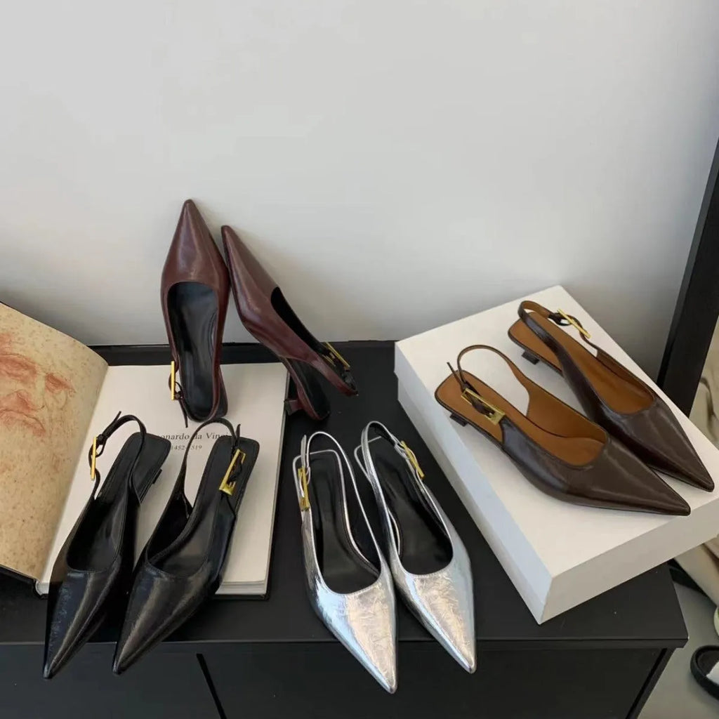 Women's black low heel pointed leather court shoe with an ankle strap on a rubber sole.