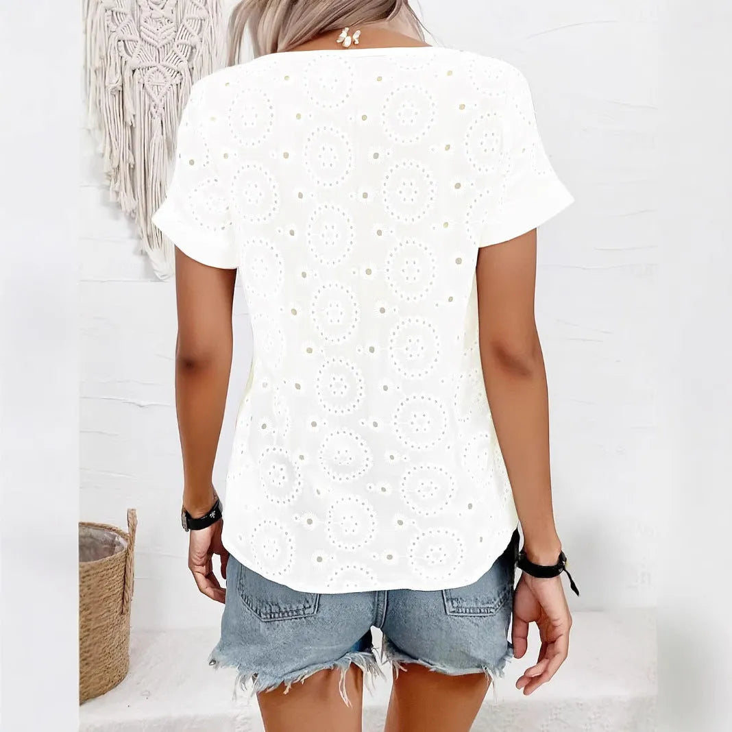 White women's V-neck t-shirt with hollow out detail and short sleeves on a hanger.