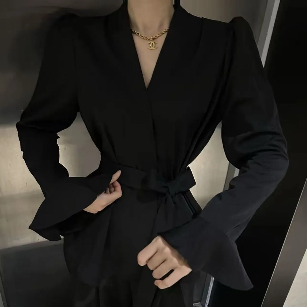 Women's black French-style shirt with an irregular collar and long bell sleeves laid flat.