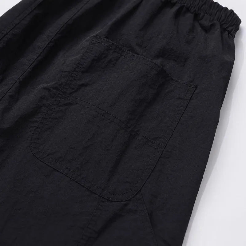 Black baggy paratrooper trousers with an elasticated drawstring waistband and three-dimensional cutting.