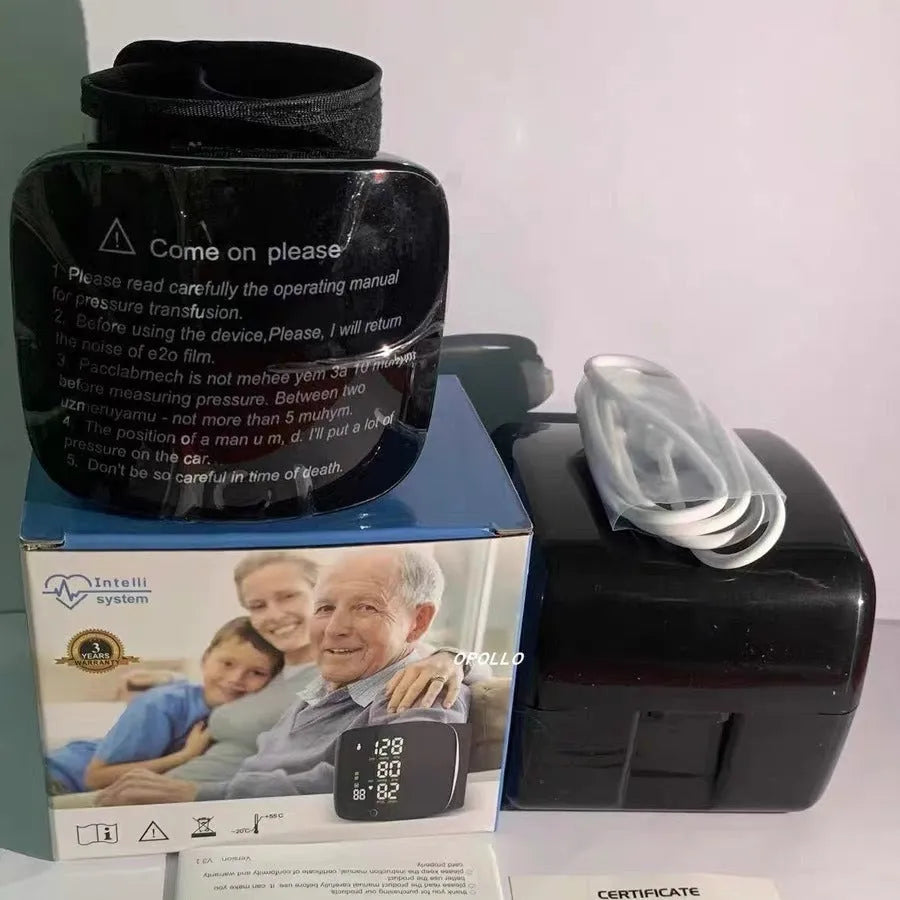 Black wrist-cuff blood pressure monitor with USB rechargeable cable on a table.