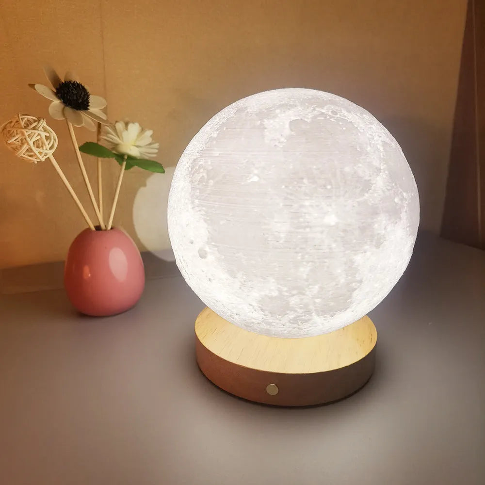 Rotating sleeping moon night lamp on a wooden base with a wire control, showing three colour options.