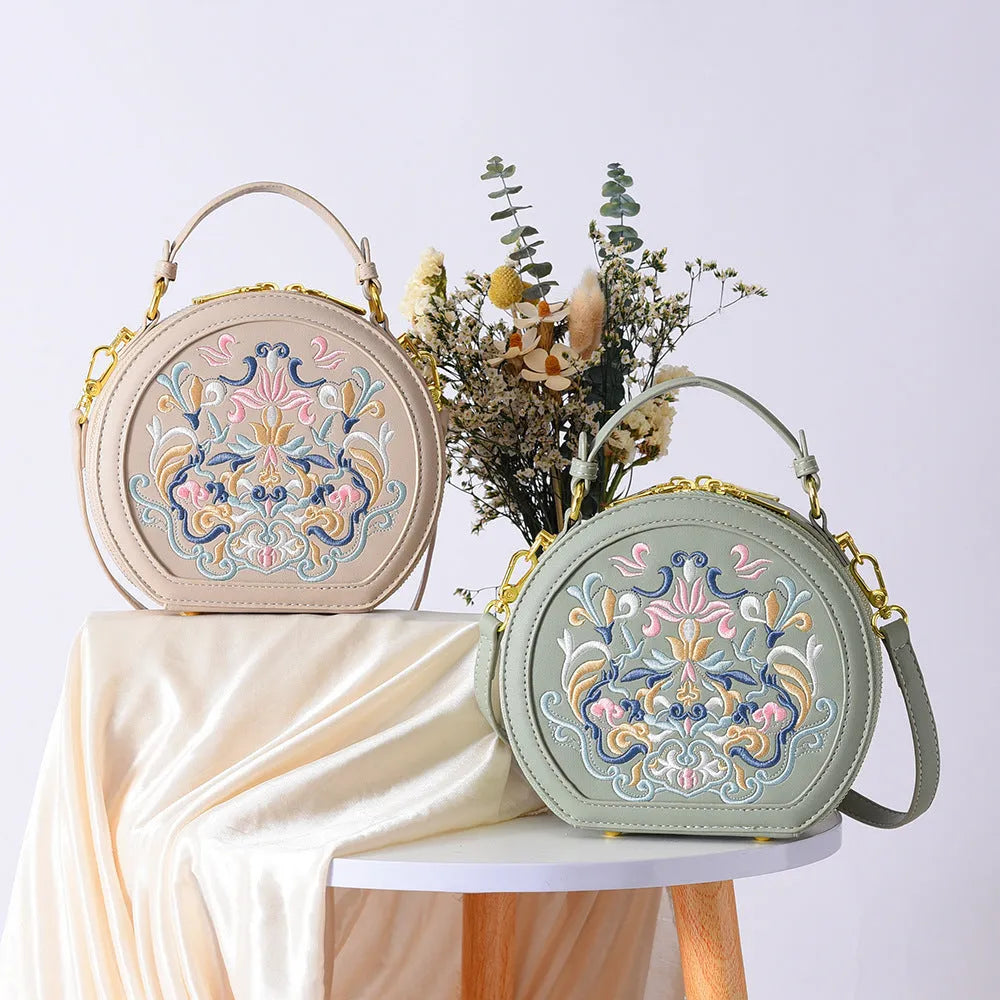 Small crossbody round bag in khaki with national-style embroidery and sewing line details, shown on a plain background