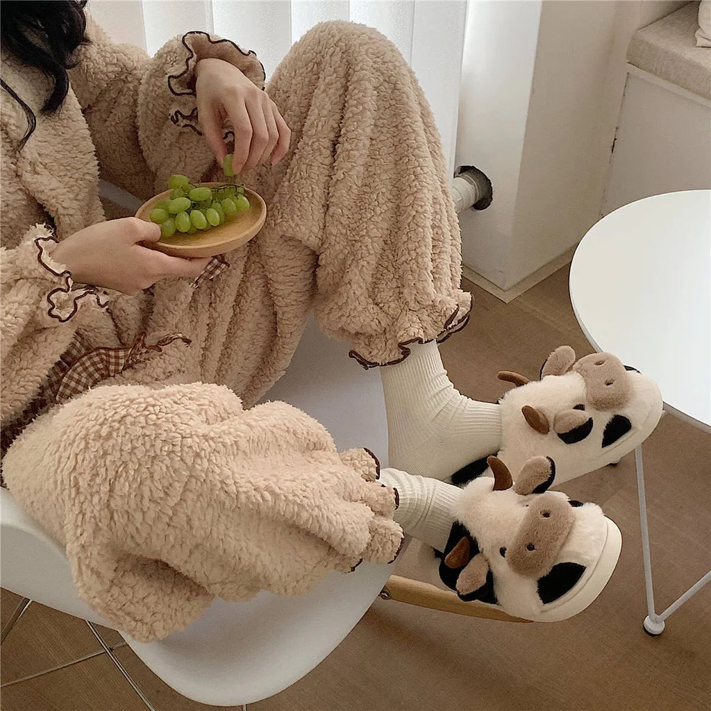 White cow-themed faux fur slippers with black spots and a textured grey anti-slip sole.
