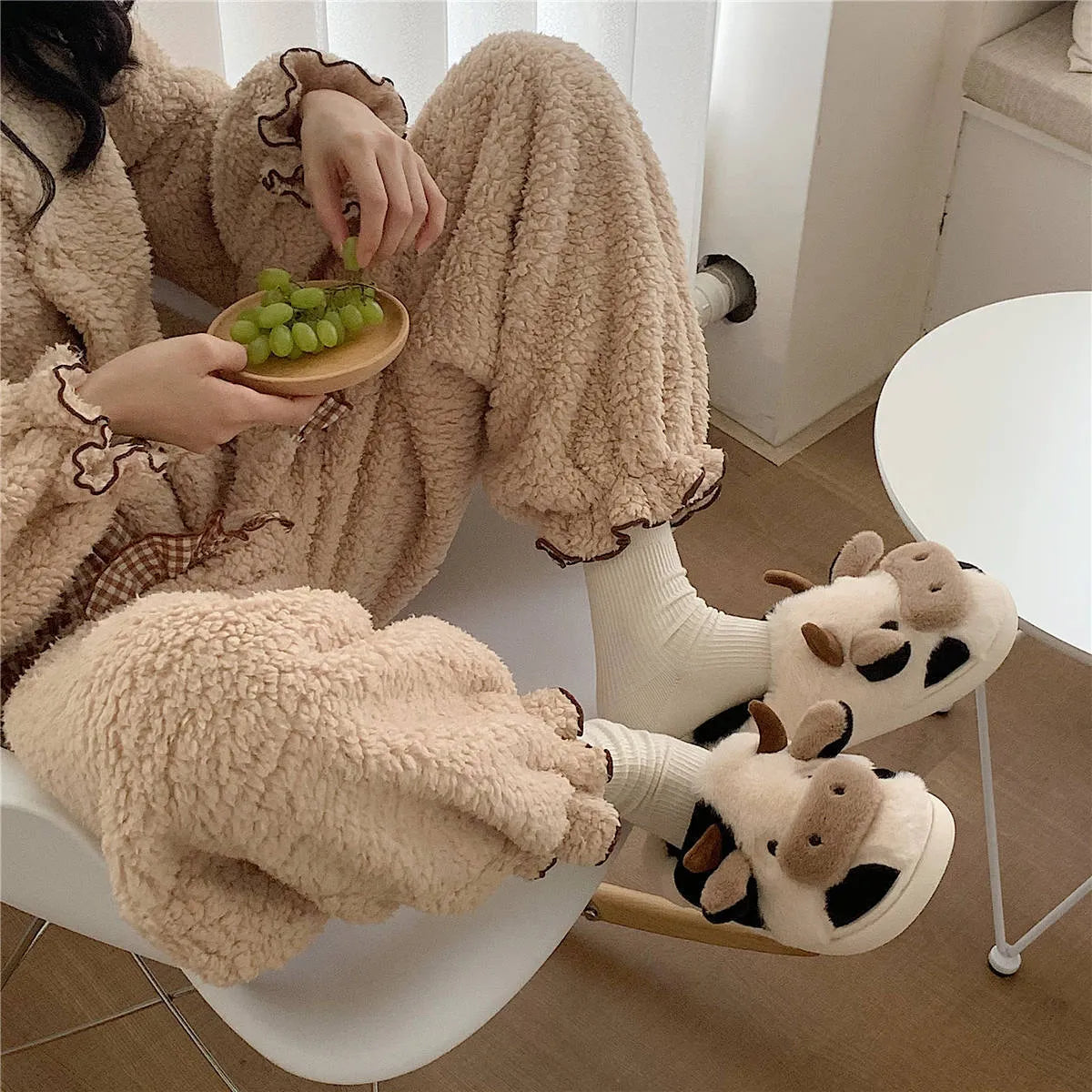 White cow-themed faux fur slippers with black spots and a textured grey anti-slip sole.