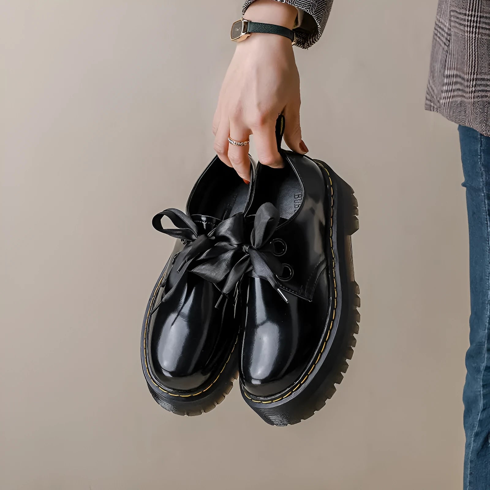 Black thick-soled women's leather shoes with cross-strap ribbons and lace-up closure on a white background.