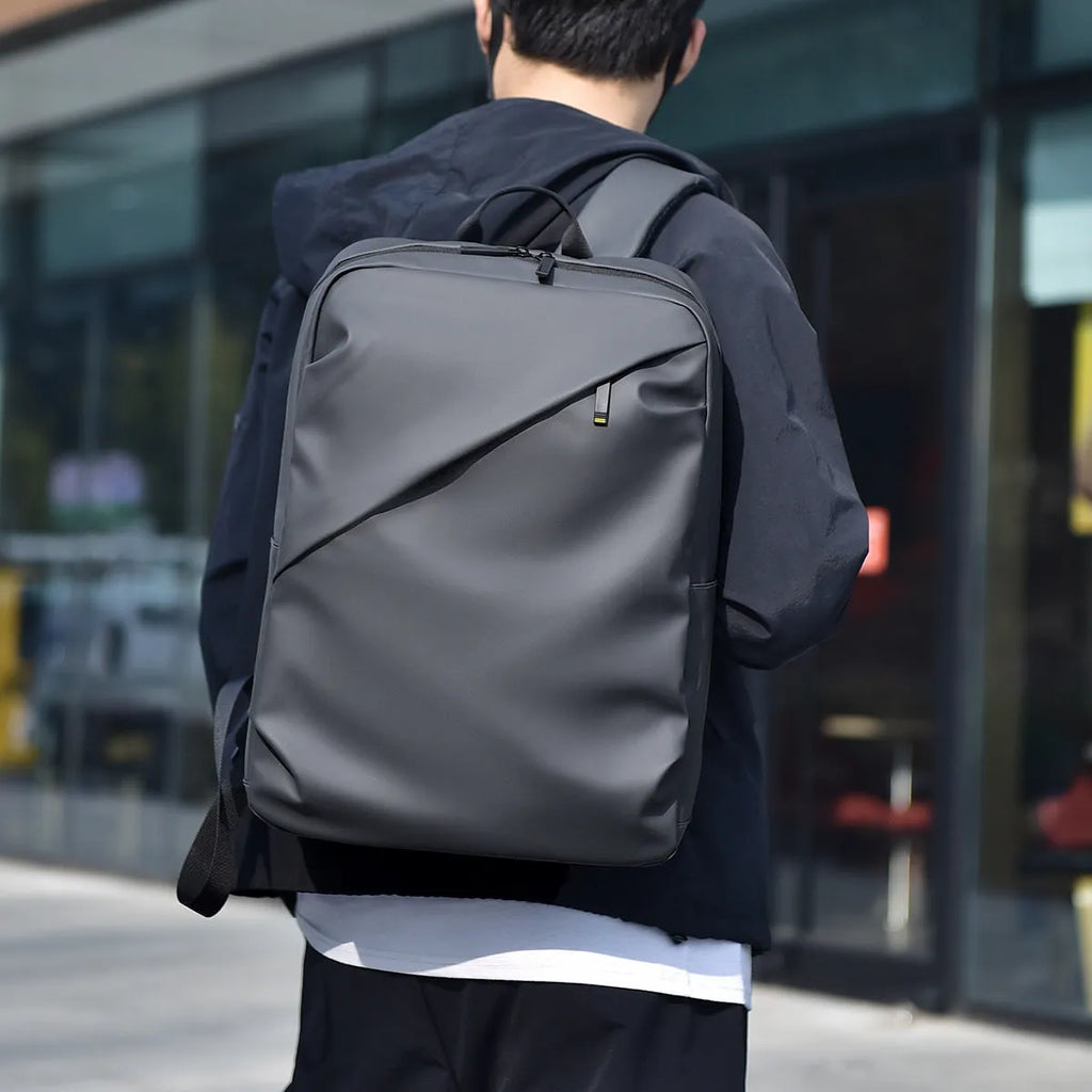 Men's large black waterproof PU backpack showing sewing thread detail and separate computer bag.