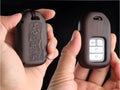 Solid ebony sandalwood key case with key rings, showing carved wood grain on a plain background