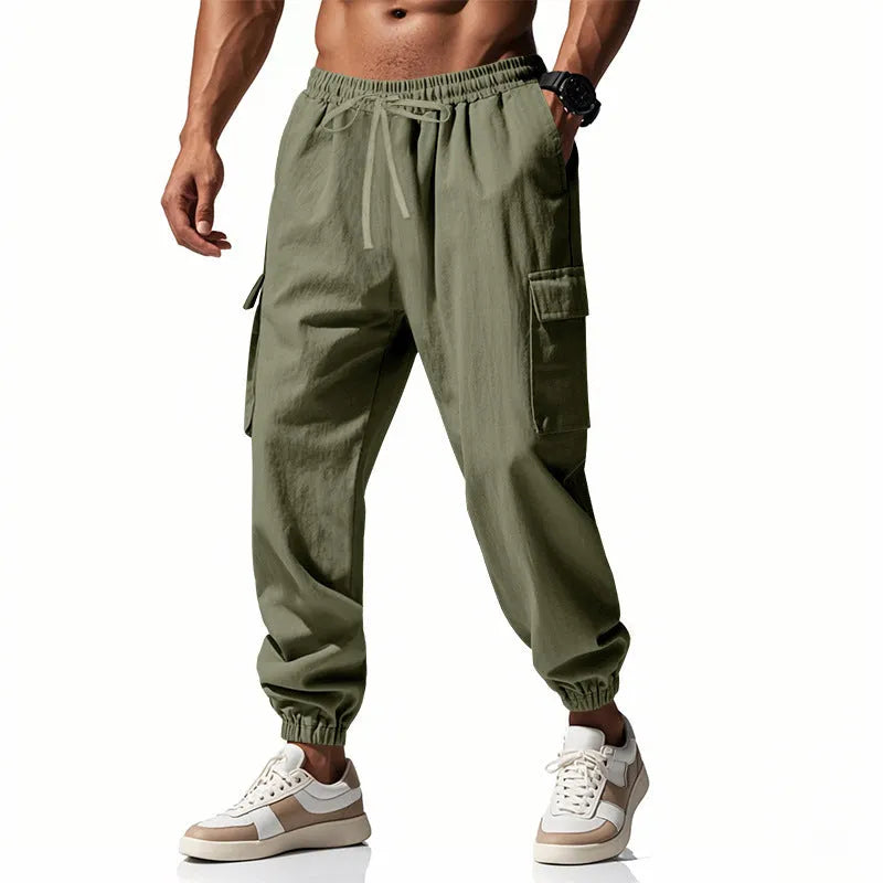 Man wearing loose khaki linen trousers with ankle-tied cuffs, drawstring waist, and multiple pockets.