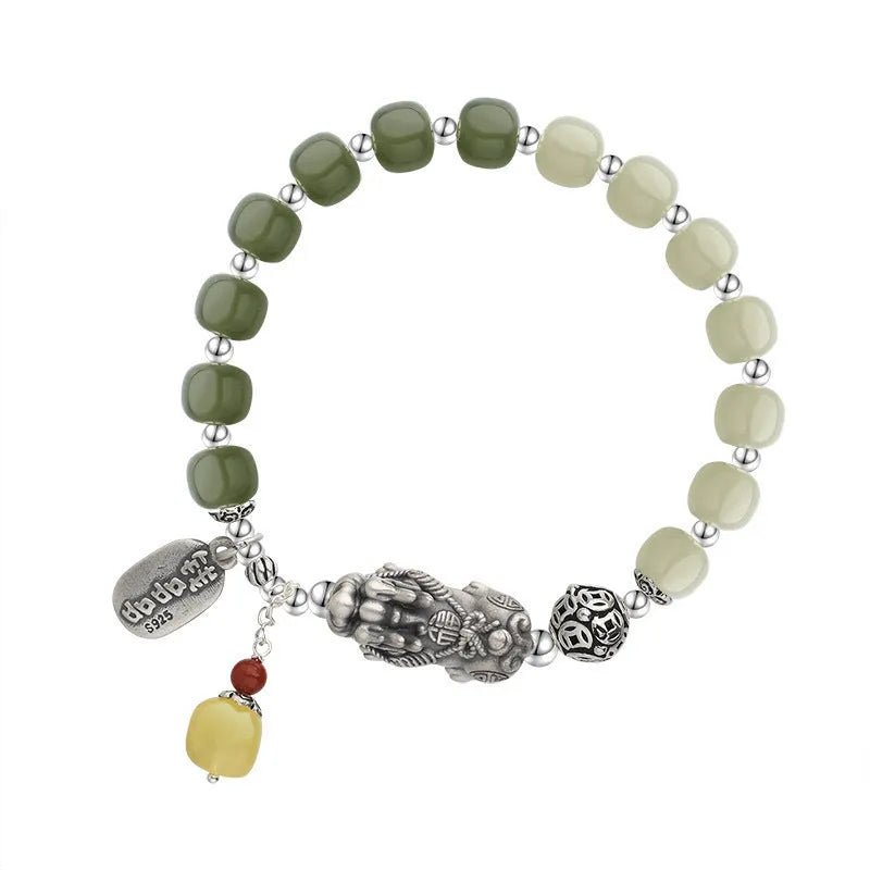 Close-up of a retro women's bracelet with a natural Hetian jade bead and a silver coin pendant on a wrist.