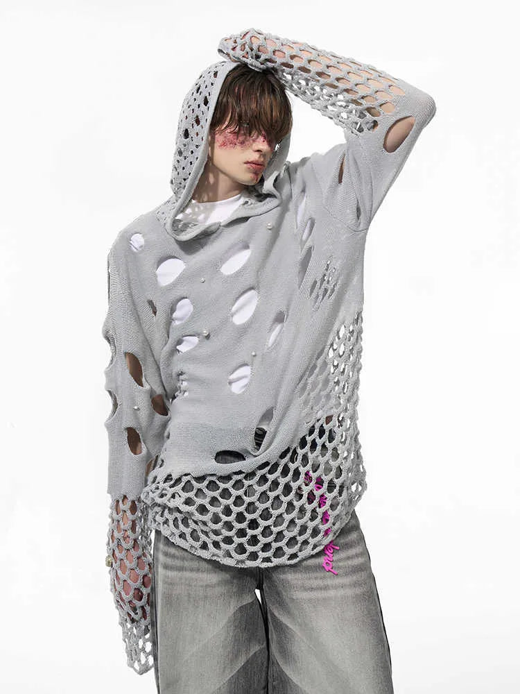 Man wearing a black loose-fit hollow knit hoodie with pearl decorations on the hood.
