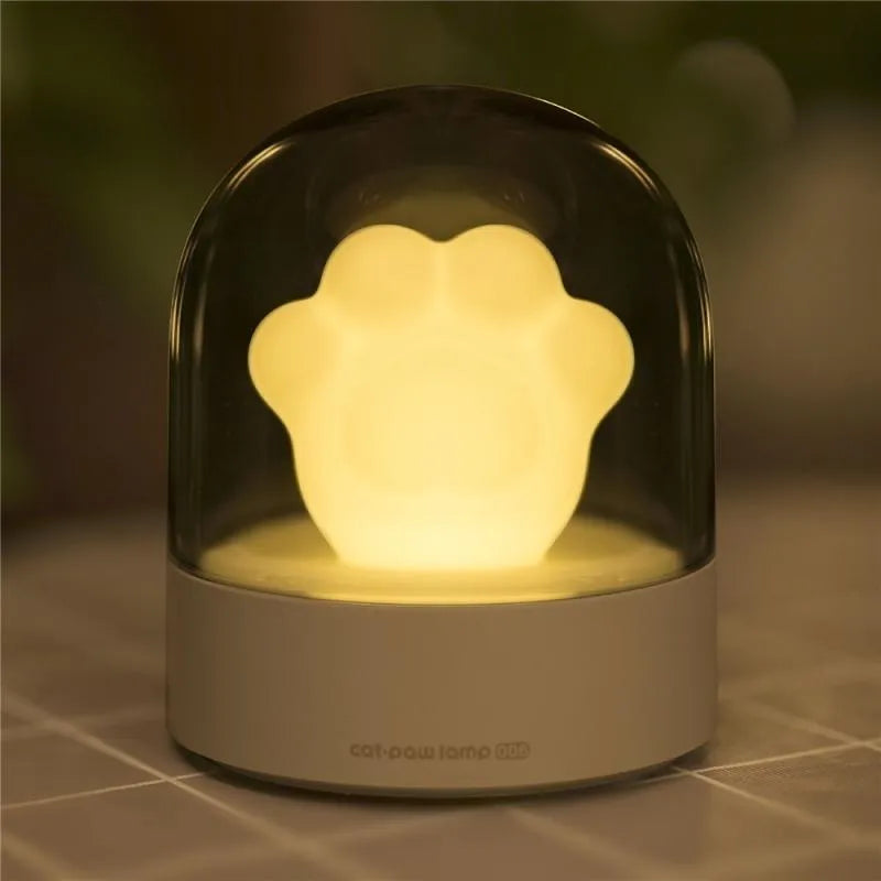 Grey cat paw shaped USB rechargeable night light with music box feature on wooden desk
