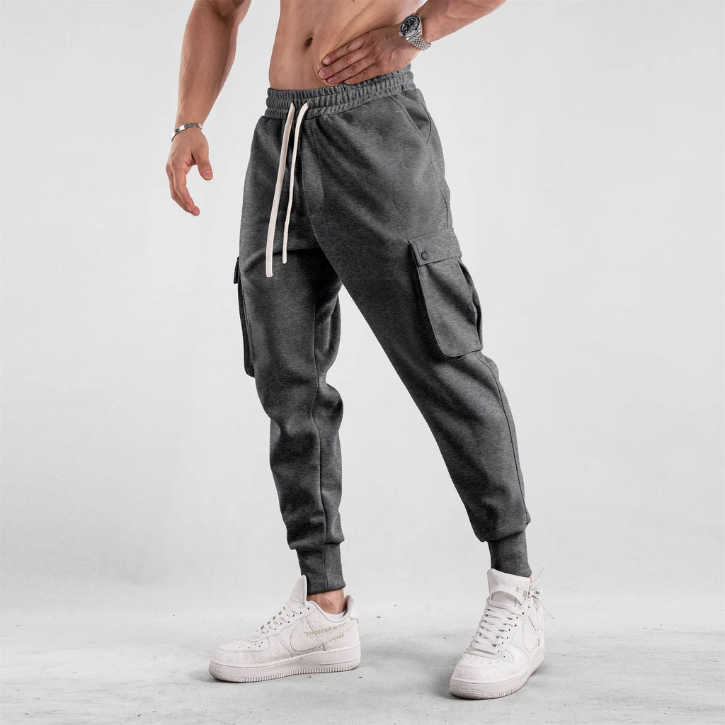 Men's loose-fit cotton sports trousers with ankle-tied cuffs and multiple pockets in a light grey colour.