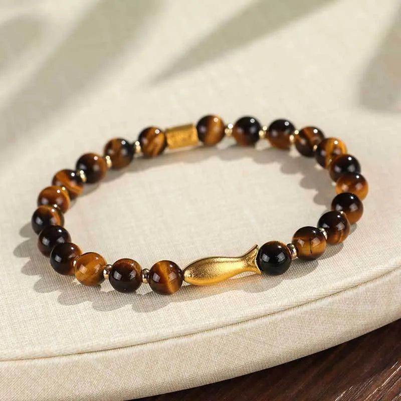 Women's tiger eye bracelet with small gold fish charm on adjustable band