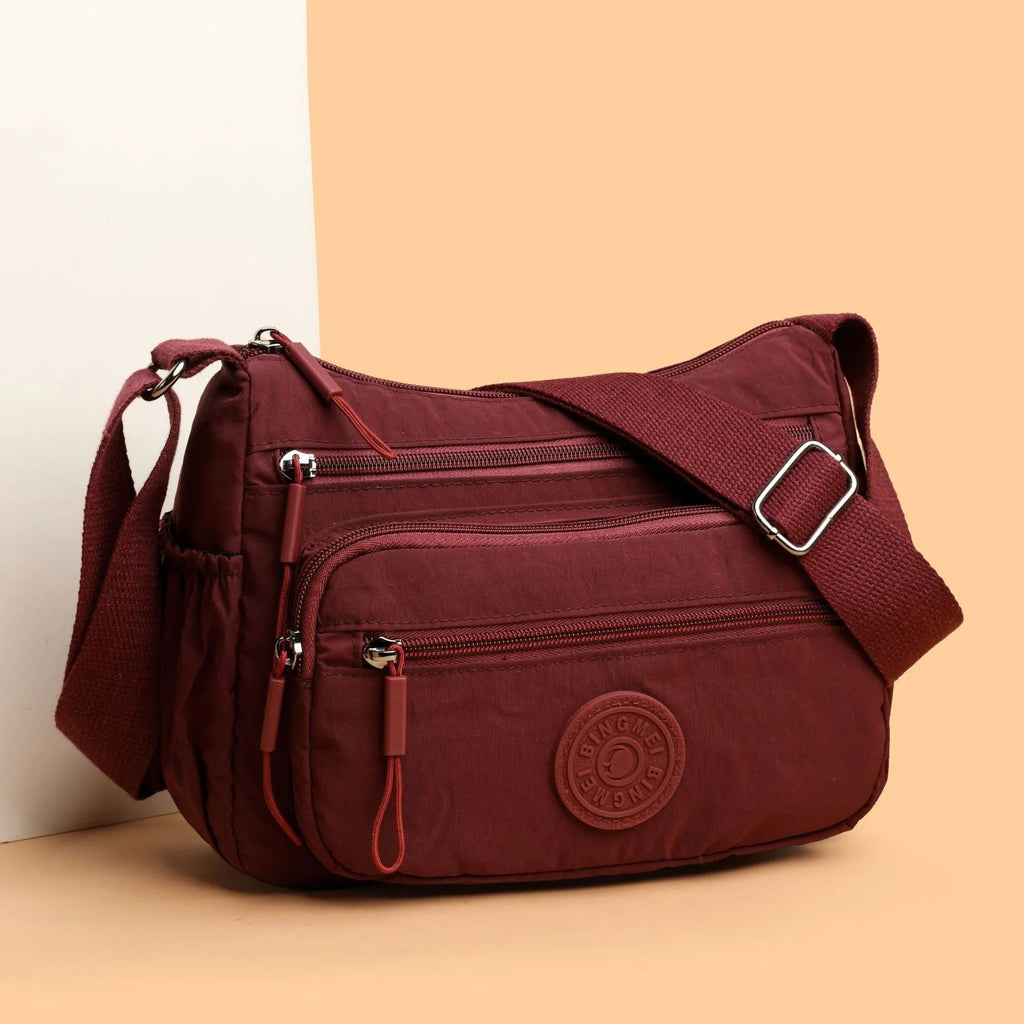 Grey water-repellent nylon crossbody bag showing three-dimensional pockets and a single shoulder strap.