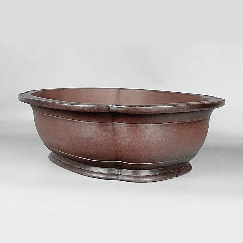 Handmade antique crabapple shaped large purple clay flowerpot on a floor.