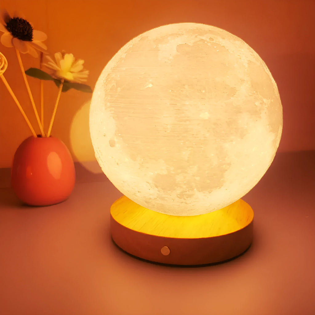 Rotating sleeping moon night lamp on a wooden base with a wire control, showing three colour options.