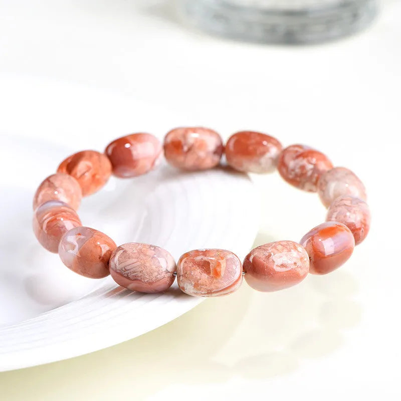 Natural cherry agate barrel bead bracelet with Ruyi charm on a white background.