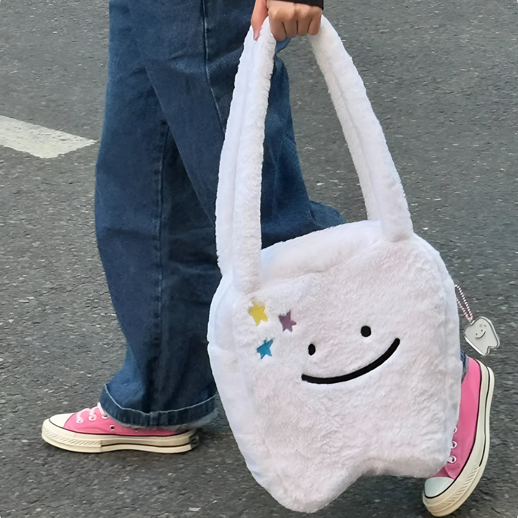 White plush tote bag with a cute teeth graphic, showing the crossbody strap and zipper opening.