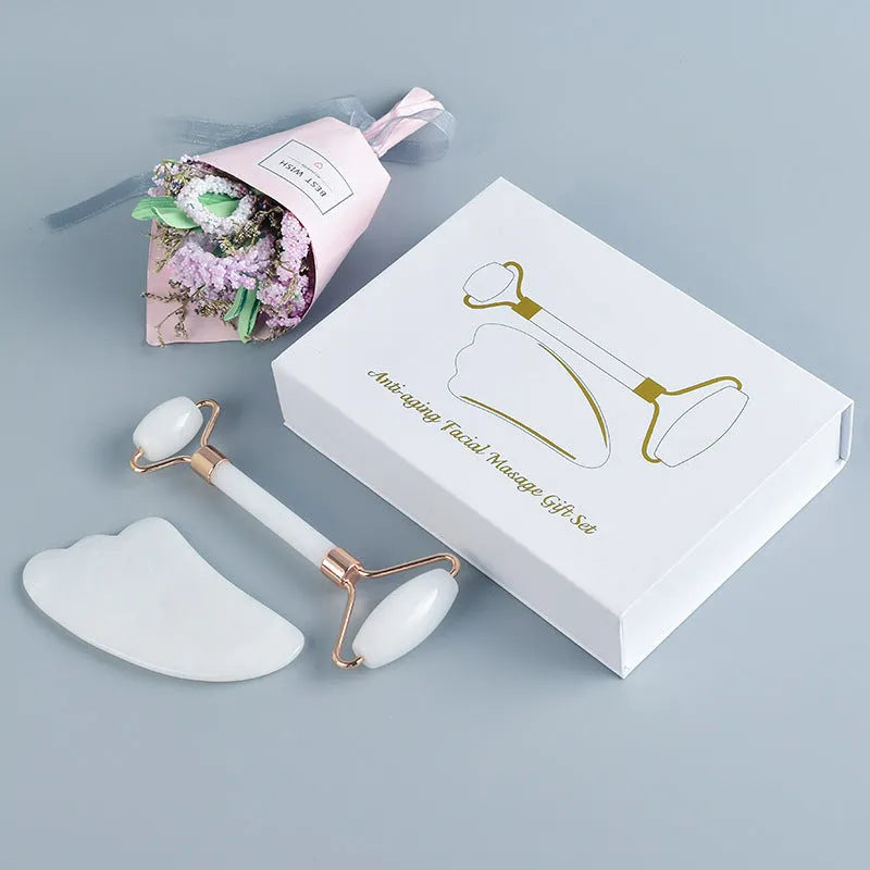 White jade double-headed facial roller and matching gua sha board set on a plain background.