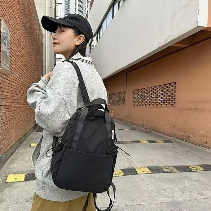 Solid colour ultra-light waterproof nylon backpack with curved shoulder straps on a white background
