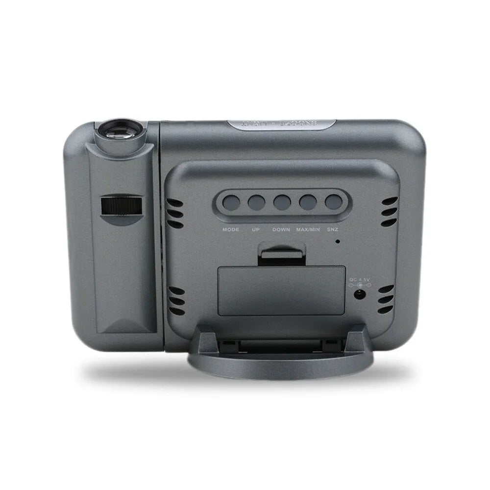 Black digital projection alarm clock on a surface, showing its compact plastic design.