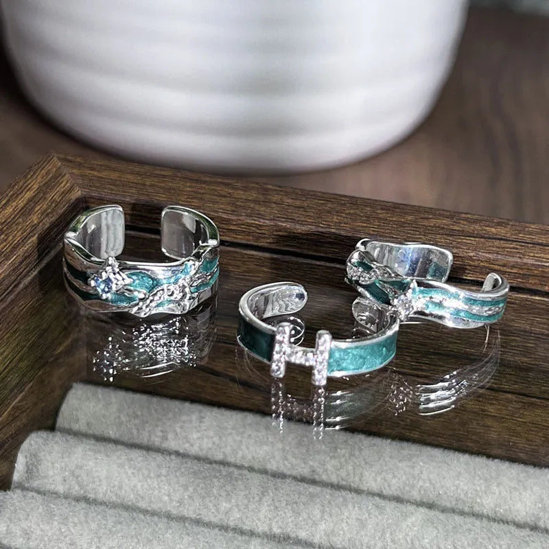 Mint green enamel eight-point asterism ring on a copper base, showing asymmetric and folded design details.