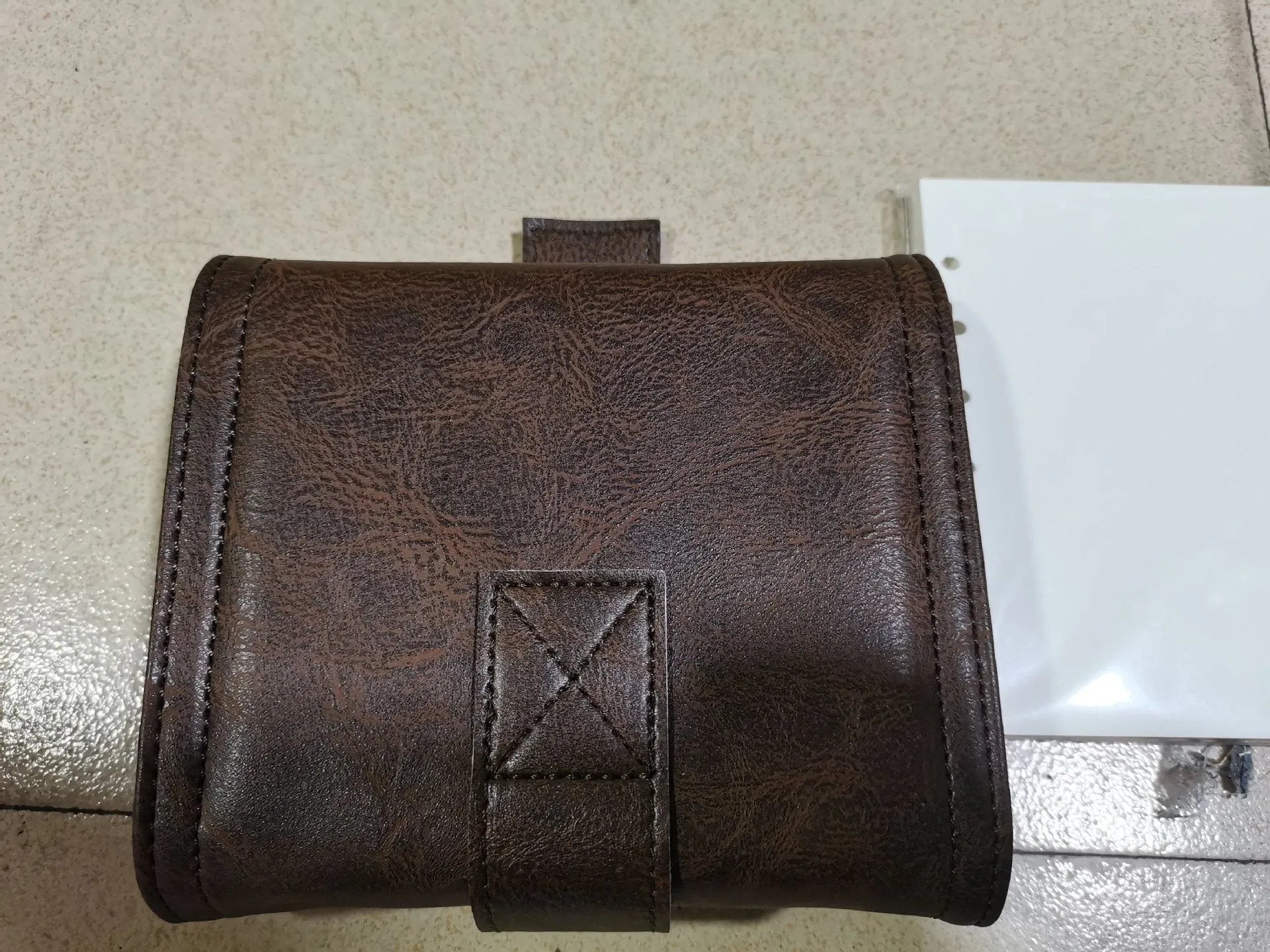Brown A7 notebook with a leather buckle closure on a PU cover, showing loose-leaf binding