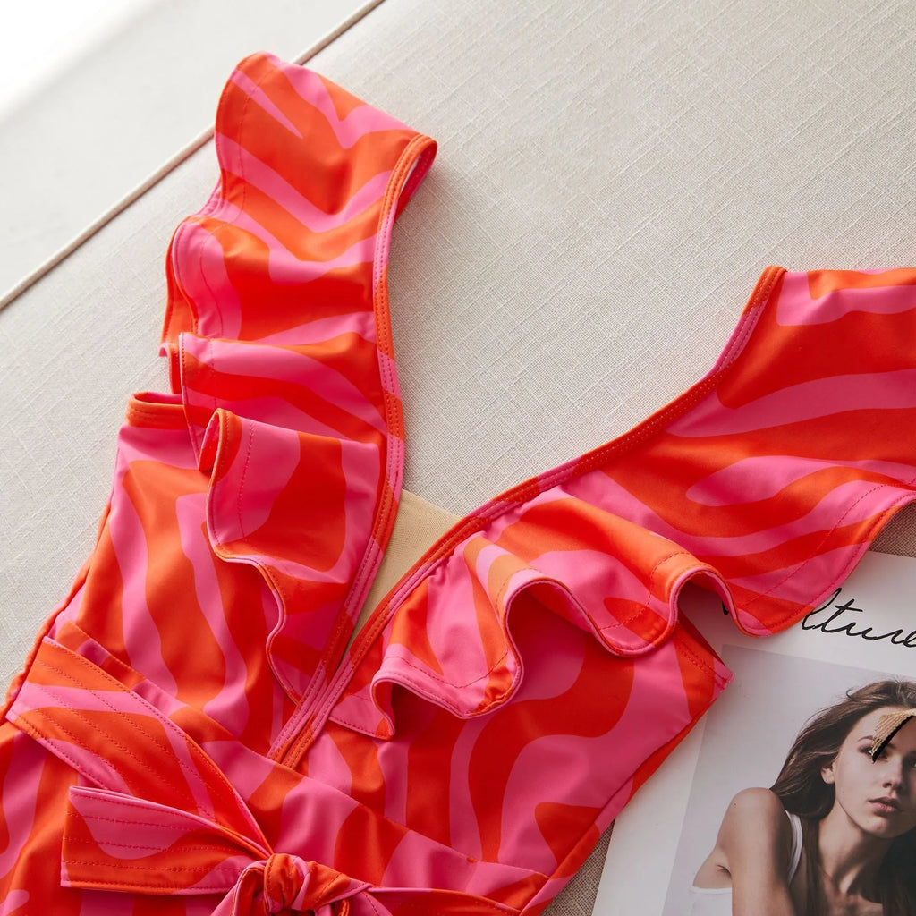 Women's printed one-piece swimsuit with ruffles on both shoulders and a deep V-neck with mesh stitching.
