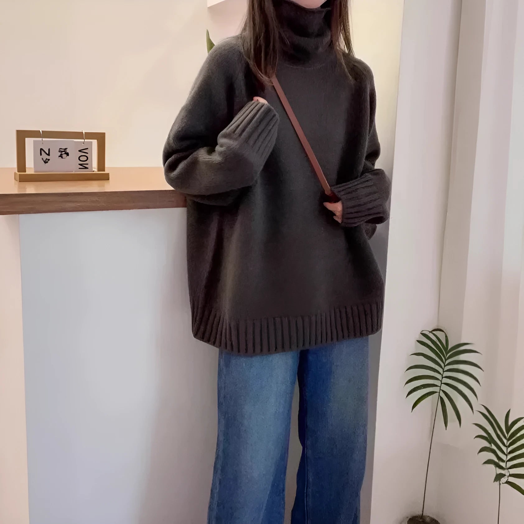 Women's loose thick grey turtleneck sweater with curling pile collar, casual pullover style.