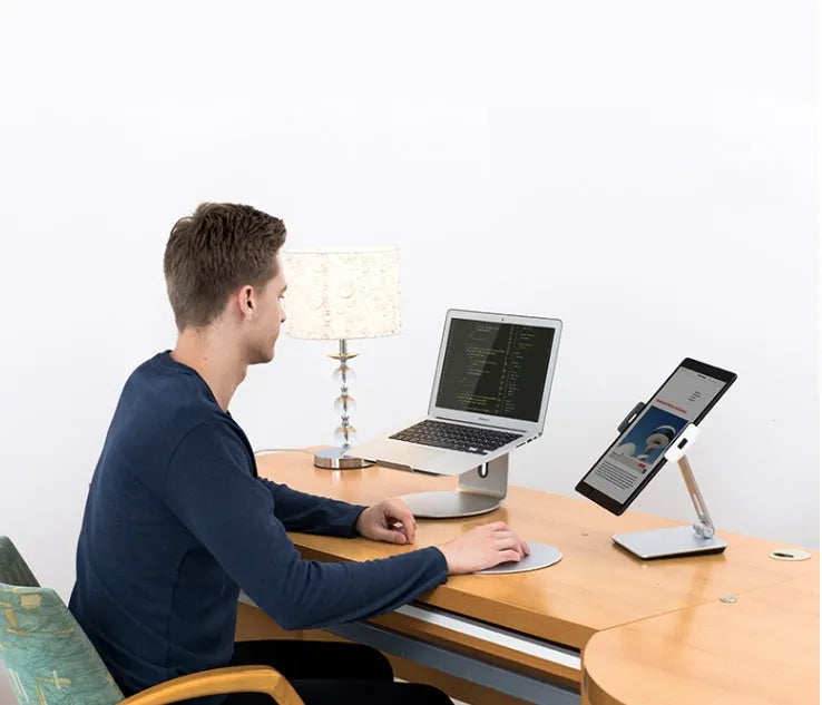 Silver aluminium foldable desktop stand holding a tablet, showing 360-degree rotation.