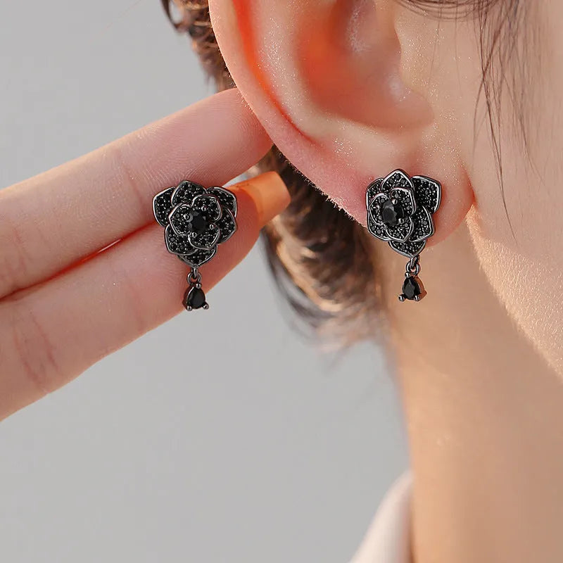 Close-up of women's black rose zircon flower stud earrings with 18K gold plating.