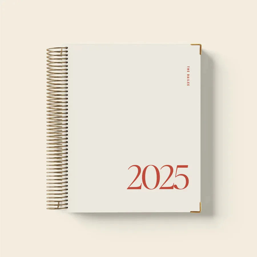Cherry red daily schedule coil notebook open to show monthly planner pages and wire-o spiral binding